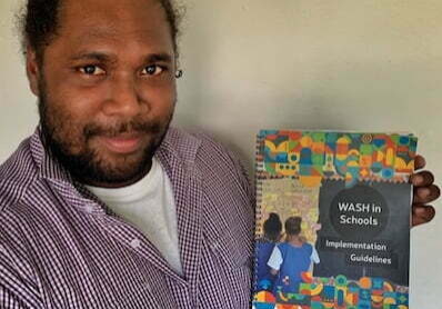 Man holding a copy of new WASH in Schools guide