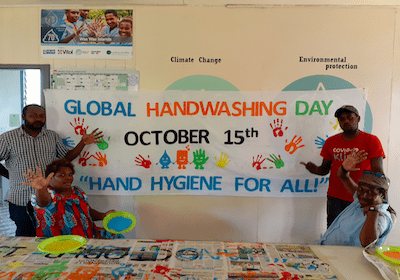 Live & Learn staff stand in front of banner that says Global Handwashing Day