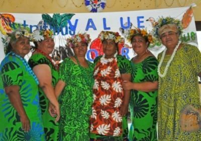 Woman involved in the Tuvalu cookbook standing in front of a banner