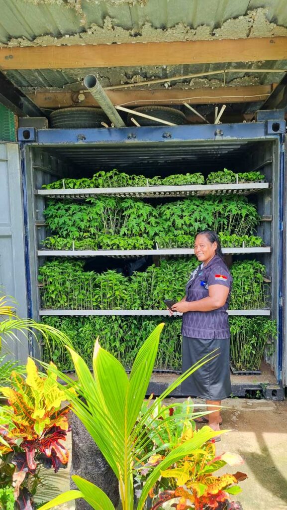A woman standing in front of shelves of growing plants