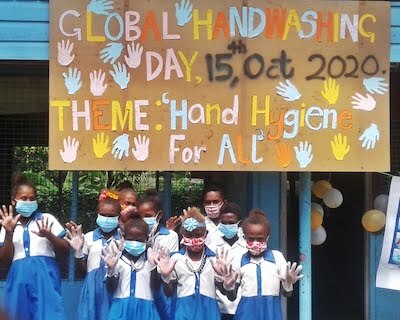 Students with facemarks in front of Global Handwashing Day sign in Solomon Islands