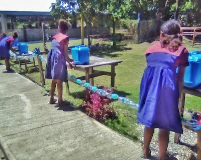 Students washing their hands with soap at safe distance from each other