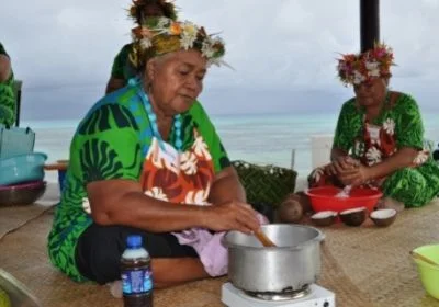 A woman in traditional Tuvaluan clothing stirring a pot of coconut cream