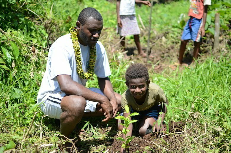 A man and boy planting a tree in a community owned protected forest