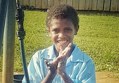 Boy washing his hands with soap at new facility in his school in Solomon Islands